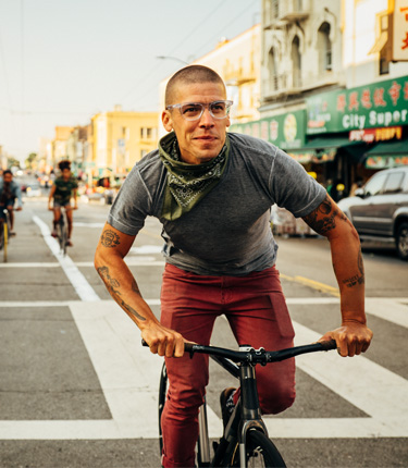 Man riding bicycle through streets smiling.