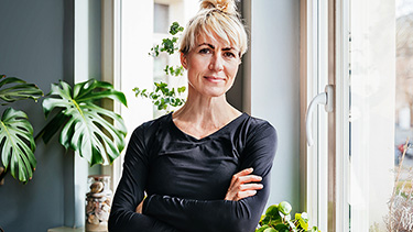 Woman with arms crossed standing next to window.