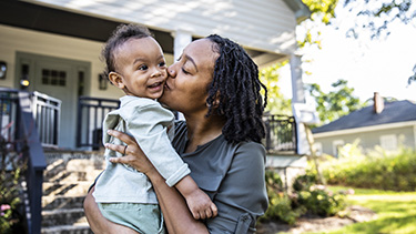 Mother kissing smiling baby.