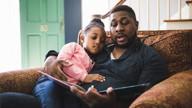 Father reading a book to his daughter.