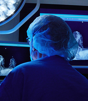 Medical professional in a dimly lit room using state-of-the-art medical technology in an operating room.