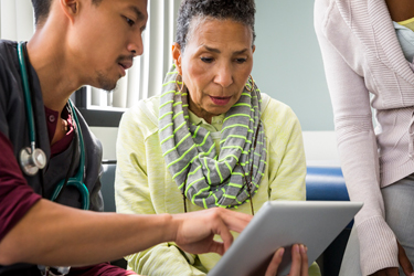 Doctor consulting patient, pointing out information on a tablet.