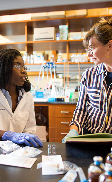 Instructor discussing text with student in laboratory.