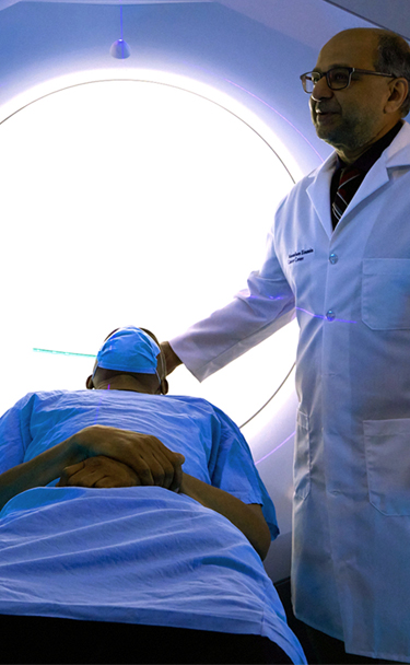 Image of patient lying down with physician next to modern cancer diagnostic machine